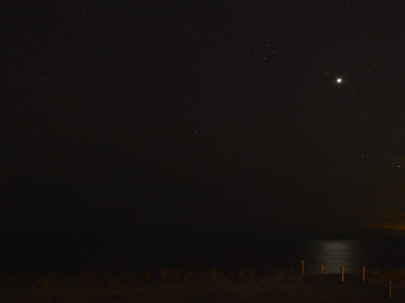 Bright planet visible over the ocean at night